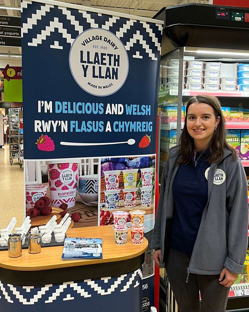 Nerys Parry standing next to a Llaeth y Llan dairy display